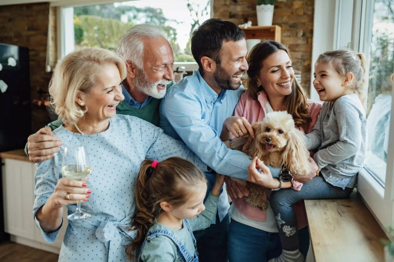 Familia feliz de varias generaciones compartiendo un momento de risas y unión en casa con su mascota.