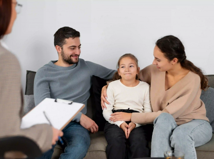 Padres brindando apoyo emocional a su hija durante una sesión de terapia familiar con una psicóloga profesional.